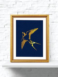 a bird flying in the air with gold paint on it's wings, against a white brick wall