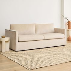 a white couch sitting on top of a wooden floor next to a vase filled with flowers