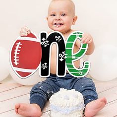 a baby is sitting on the floor holding up a sign that says me and football