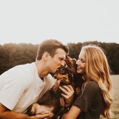 a man and woman holding a dog in their hands