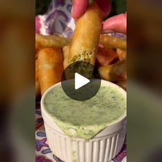 a person dipping something in a bowl with some breadsticks on the other side