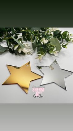 three star shaped metal tags with green leaves on the side and white flowers in the background