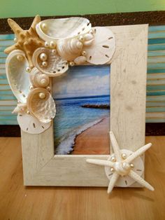 a frame with seashells and starfish on the beach in front of a window