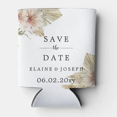 save the date card with flowers and leaves on white paper, hanging from a metal hook