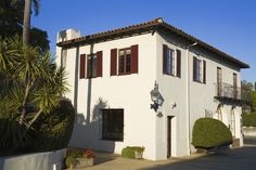 a white house with red shutters and trees