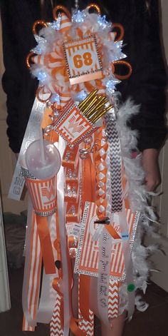 an orange and white christmas tree is decorated with ribbons, tags, lights and decorations