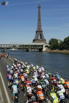 a large group of bicyclists riding down the road in front of the eiffel tower