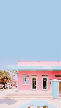 a pink and blue building with a picnic table in front of it