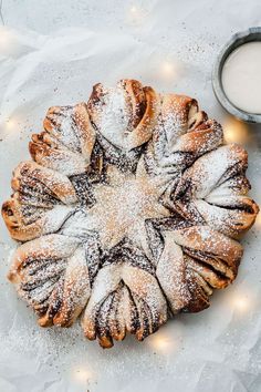 a cake with powdered sugar on top next to a glass of milk and some lights