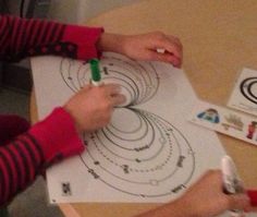 two people are drawing circles on paper with crayons