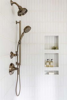 the shower head and handset are connected to the wall in this white tiled bathroom