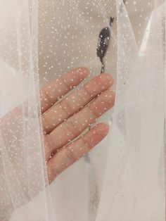 a person's hand holding onto a piece of plastic with water droplets on it