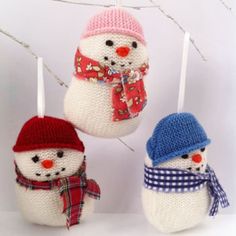 three knitted snowman ornaments hanging from a tree