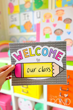 a person holding up a welcome to our class sign in front of colorful storage bins