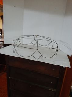 a metal bowl sitting on top of a white paper covered dresser next to a wall