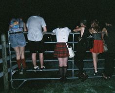 some people are standing in front of a fence with their backs turned to the camera