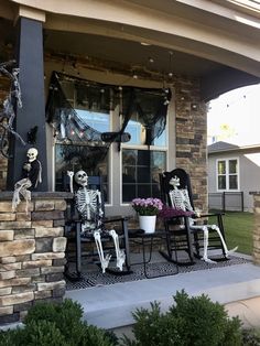 two skeletons sitting on chairs in front of a house