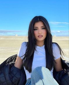 a woman with long black hair sitting on the ground