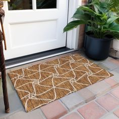 a door mat on the ground next to a potted plant