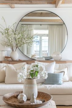 a living room filled with furniture and a large round mirror above the coffee table on top of a wooden tray