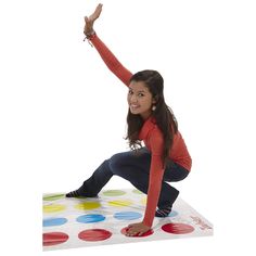 a woman kneeling on top of a colorful polka dot mat with her arms in the air