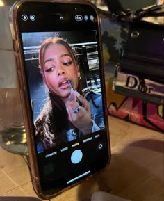 a cell phone with an image of a woman brushing her teeth on the screen, sitting on a table