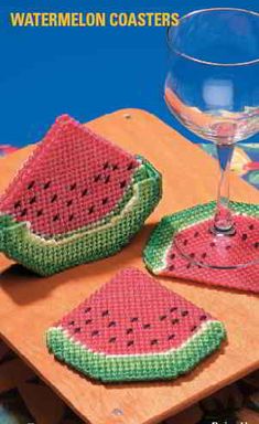 two watermelon coasters on a wooden table next to a glass of wine