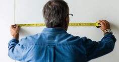 a man measuring the wall with a tape measure