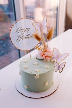 a birthday cake decorated with flowers and butterflies on a table in front of a window