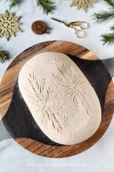 a wooden cutting board topped with a doughnut on top of a table next to christmas decorations