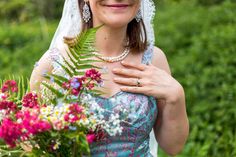 a woman in a wedding dress holding a bouquet of flowers and smiling at the camera