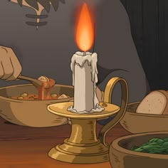 a lit candle sitting on top of a wooden table next to bowls and pans