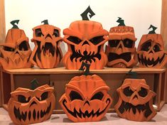 carved pumpkins with faces and mouths on display in front of a wooden shelf filled with halloween decorations