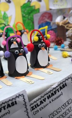 penguins made out of popsicle sticks on a table with other items in the background