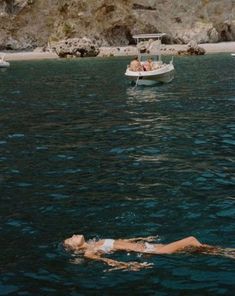 two people floating in the water near a boat