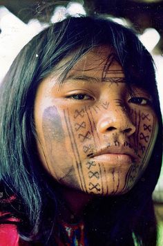 an native american woman with painted face and body art on her face, looking at the camera