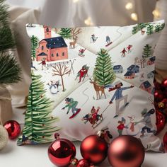 a christmas pillow sitting on top of a table next to ornaments