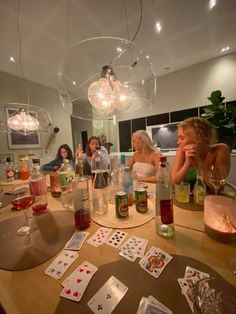 a group of people sitting around a table with cards and wine glasses on top of it