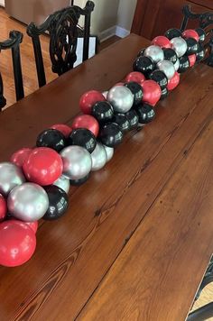 a wooden table topped with lots of black and red balls