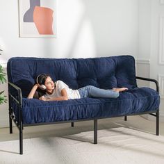 a woman laying on top of a blue couch