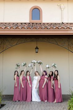 a group of women standing next to each other in front of a building with flowers