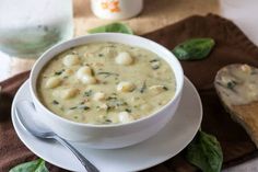 a white bowl filled with soup on top of a table next to a wooden spoon