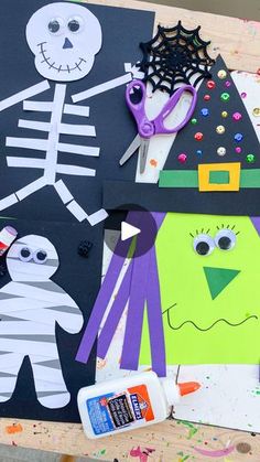 paper cut outs and crafting supplies sitting on top of a wooden table with halloween decorations