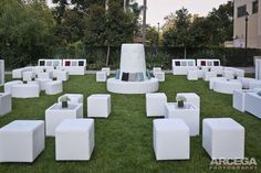 white cubes are arranged on the grass in front of a building with trees and bushes