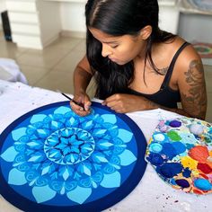 a woman sitting at a table working on an art project