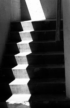 black and white photograph of stairs leading up to the top floor with sunlight coming through