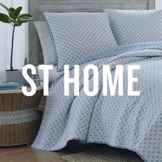 a bed with blue and white comforter in front of a wooden headboard that says st home