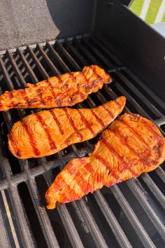 three pieces of meat cooking on a grill