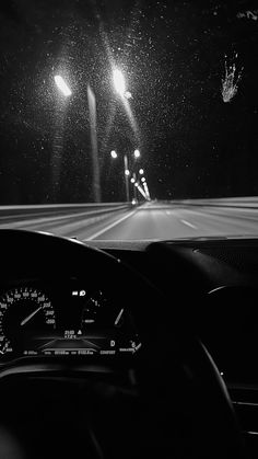 the dashboard of a car at night with street lights and traffic signals in black and white