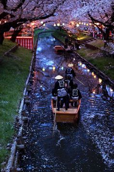 three people are riding in a small boat on the water with umbrellas over their heads